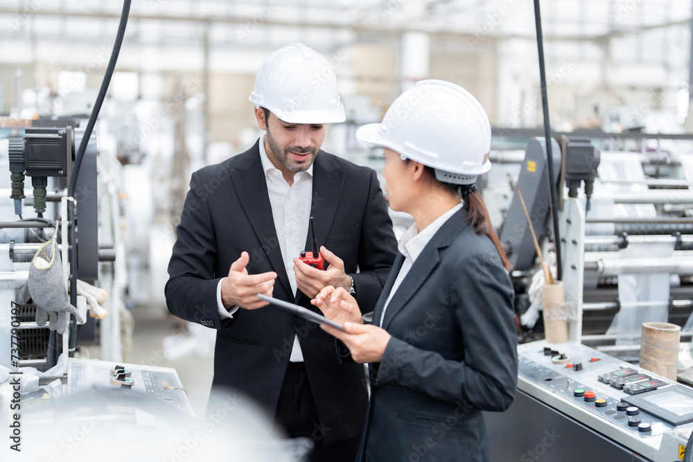 European male architectural engineers and senior officials Asian woman Analyze machinery systems and view projects via tablet. Wear a suit and safety helmet in the material manufacturing industry. European male architectural engineers and senior officials Asian woman Analyze machinery systems and view projects via tablet. Wear a suit and safety helmet in the material manufacturing industry.