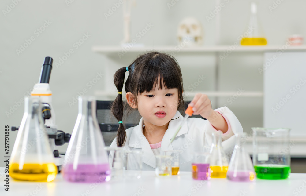 Asian little cute girl students in lab coat making test tube science experiments chemical laboratory in study room at school. Education research and development concept learning kids.
