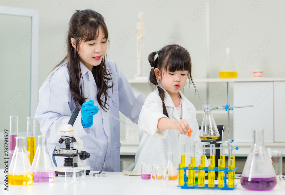 Asian woman teacher and little children girl making science experiments tests in chemical laboratory study room. Education research and development concept learning for kids. Asian woman teacher and little children girl making science experiments tests in chemical laboratory study room. Education research and development concept learning for kids.