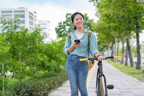 Happy Asian woman in casual clothes using a smartphone and a bicycle