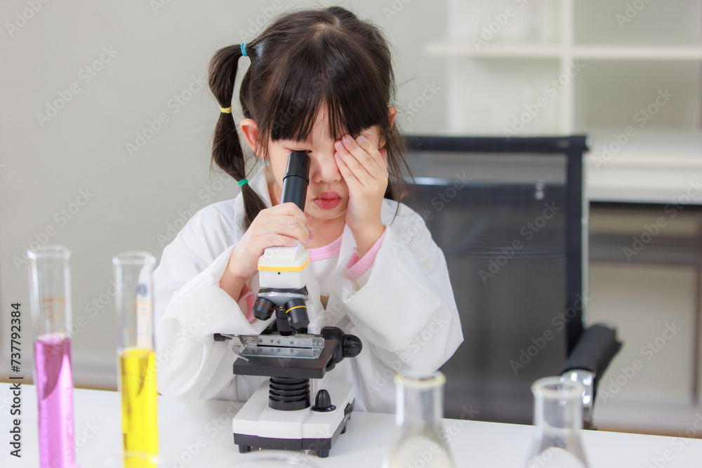 Asian little girl students in lab coat making test tube science experiments and looking microscope chemical laboratory in study room at school. Education research and development concept learning kids Asian little girl students in lab coat making test tube science experiments and looking microscope chemical laboratory in study room at school. Education research and development concept learning kids