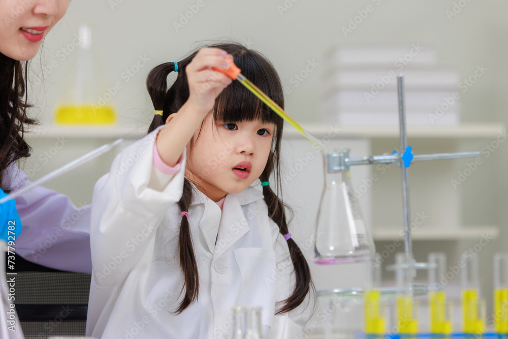 Asian woman teacher and little children girl making science experiments tests in chemical laboratory study room. Education research and development concept learning for kids. Asian woman teacher and little children girl making science experiments tests in chemical laboratory study room. Education research and development concept learning for kids.