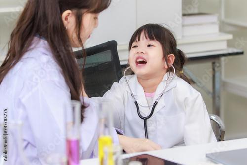 Asian woman doctor and cheerful little girl applying medical stethoscope at doctor appointments in laboratory lab. Education healthcare, medicine childrens hospital concept learning for kids