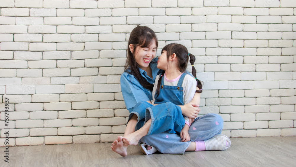 Happy asian beautiful young mother and cute daughter little girl smiling posing hugging on white brick wall background studio portrait Mother's Day love family parenthood childhood concept.