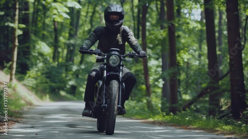 A guy riding a motorcycle on a road in a forest, green trees in the background