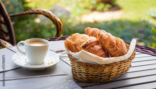 Breakfast with coffee and croissants in a basket on table, selective focus; breackfast; morning outdoor scene photo