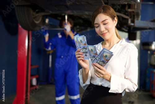 businesswoman or customer holding and counting cashes pay for technician in automobile repair shop