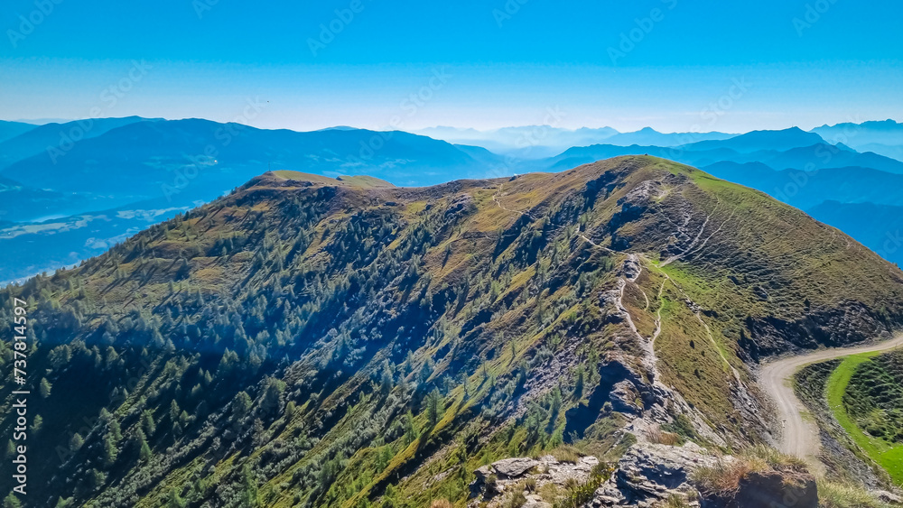 Fototapeta premium High alpine road to mountain resort Goldeck, Latschur group, Gailtal Alps, Carinthia, Austria. Looking at magical mountain peaks of Karawanks and Julian Alps seen from, EU. Austrian Alps in summer