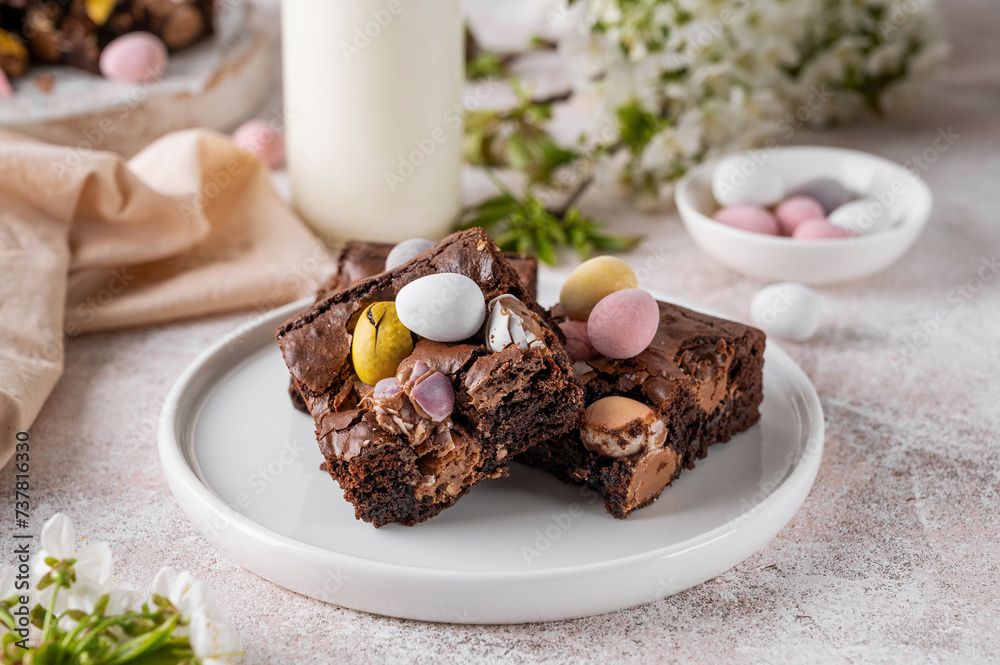 Chocolate brownie with Easter candies in the form of colored eggs with a bottle of milk. Easter dessert. Copy space. Chocolate brownie with Easter candies in the form of colored eggs with a bottle of milk. Easter dessert. Copy space.