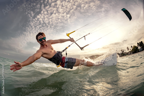Fast kite surfer rides at sunset sea beach. Close up photo with hand and kite in sky
