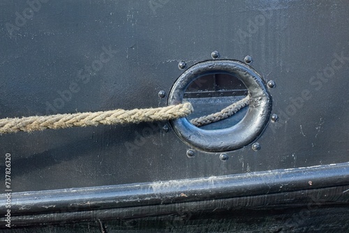 Slika na platnu Closeup of a thick twisted mooring rope coming out of hole in the side of a metal ship