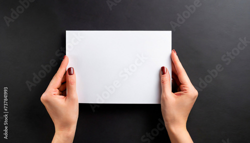 Female hands holding an empty white piece of paper with a black background. Space for text, copy and other graphics. ai generated.