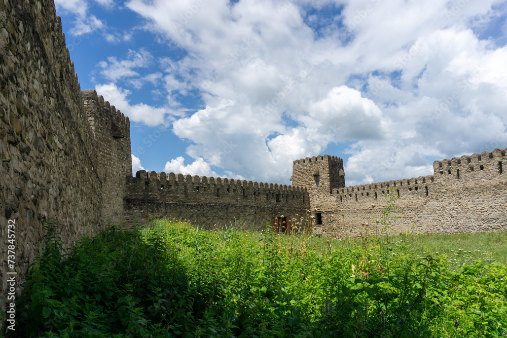 Medieval fortress wall and tower. Day light, blue sky and clouds. Georgia.