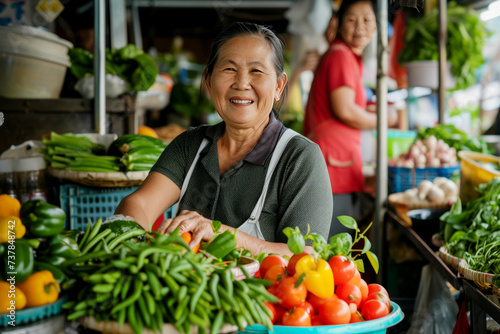 Cheerful senior woman vendor selling a variety of fresh vegetables at a local market stall with a smile.