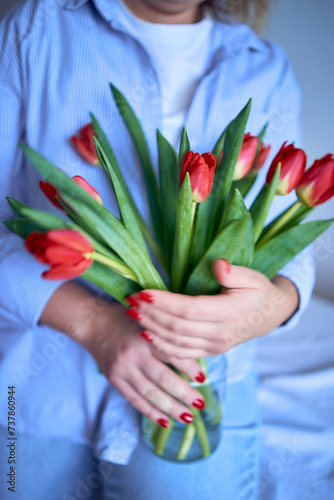 a medium-sized woman holds a bouquet of red tulips in her hands photo