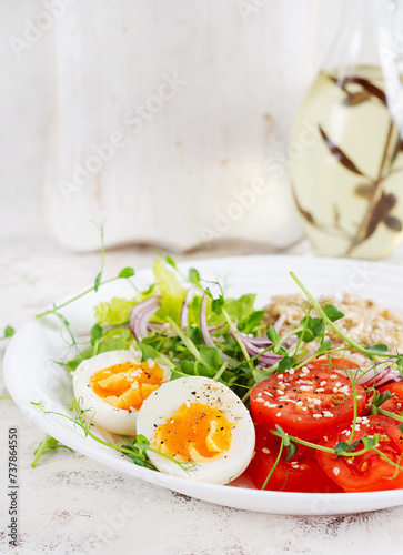 Breakfast oatmeal porridge with boiled eggs and fresh vegetables. Healthy balanced food. Trendy food.