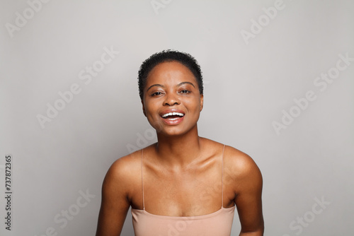 Emotional positive healthy young woman with dark shiny skin smiling looking at camera on white background. Cosmetology, skincare, facial treatment concept