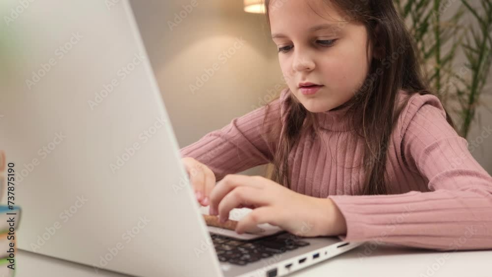 Pupil engaged in distance learning. Child participating in a video call. Exhausted tired Caucasian little brown haired girl using laptop studying online at home writing down information Pupil engaged in distance learning. Child participating in a video call. Exhausted tired Caucasian little brown haired girl using laptop studying online at home writing down information