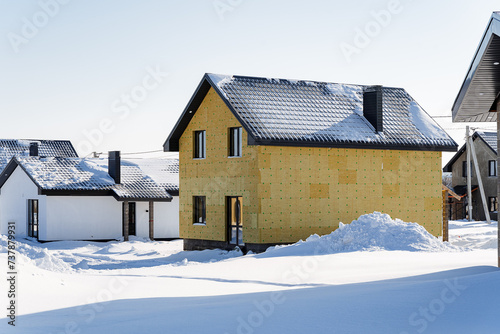 Winter in a cottage village, a country house stands in the snow, the facade insulation is made of mineral wool, a finished built house.