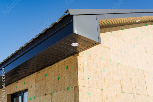 Foto Thermal insulation of the house, exterior view, roof of the house lined with corrugated sheets, lamp on the facade of the building, mineral wool in the decoration of the dwelling