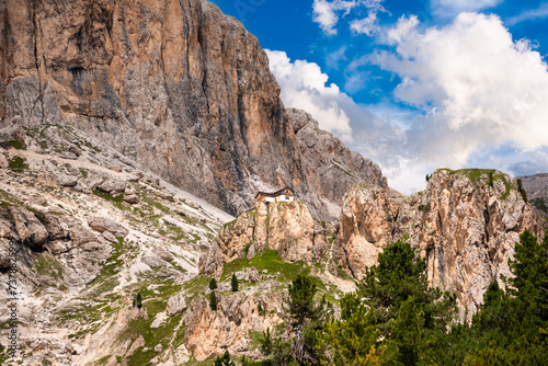 Dolomite alps and a house or mountain refuge on rock above