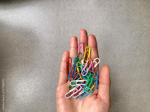 Hand Holding Colorful Paper clip for paper documents in the office. Office essential tools for paperwork photo
