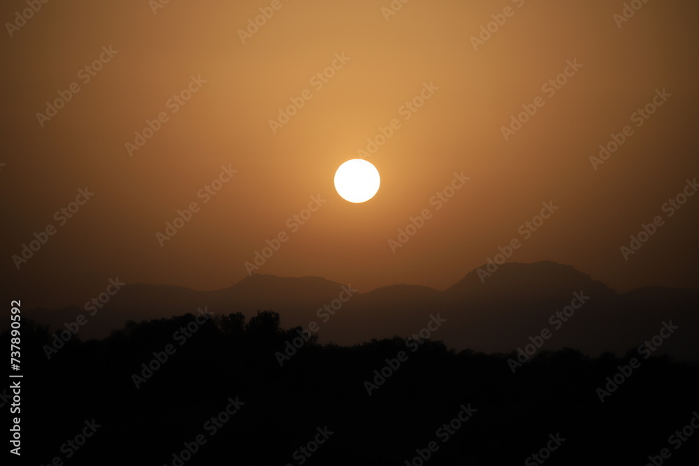 setting sun above a mountain range in hazy sahara desert dust light setting sun above a mountain range in hazy sahara desert dust light