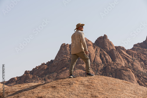 A man on a cliff hiking and looking forward. Active Holidays. Natural Colors.