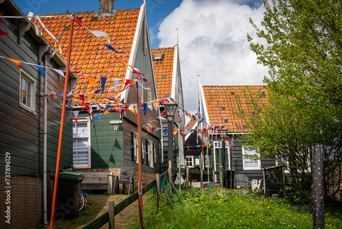 Fototapeta Naklejka Na Ścianę i Meble -  Street filled with flags in the village of Marken with traditional colorful houses in Holland Dutch island peninsula the IJsselmeer Marken on the IJsselmeer in the Netherlands.