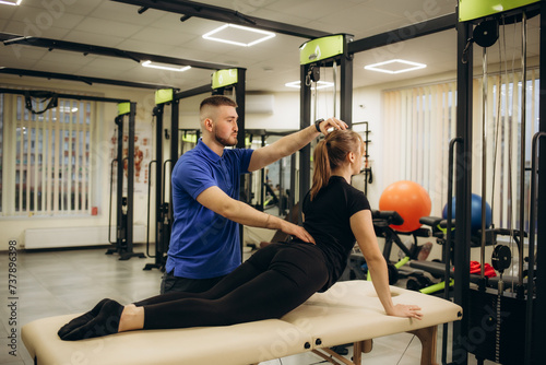Professional chiropractor or physiotherapist helps to heal a young woman's back. Doctor fixes the patient lying on a couch of a modern rehabilitation clinic Concept of physical rehabilitation.