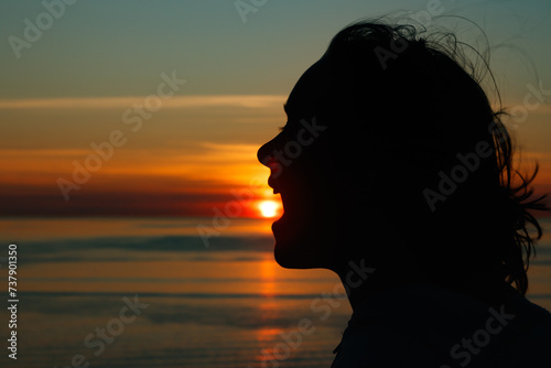 Girl silhouette with open mouth in magical sunset over the Gulf of Finland, Baltic sea. photo