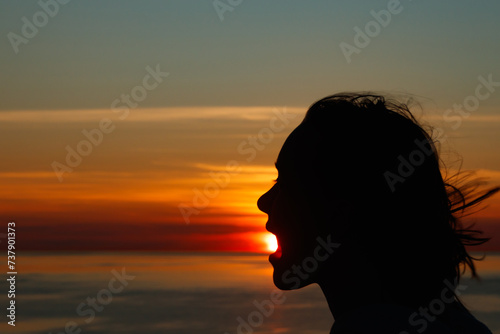 Girl silhouette with open mouth in magical sunset over the Gulf of Finland, Baltic sea.