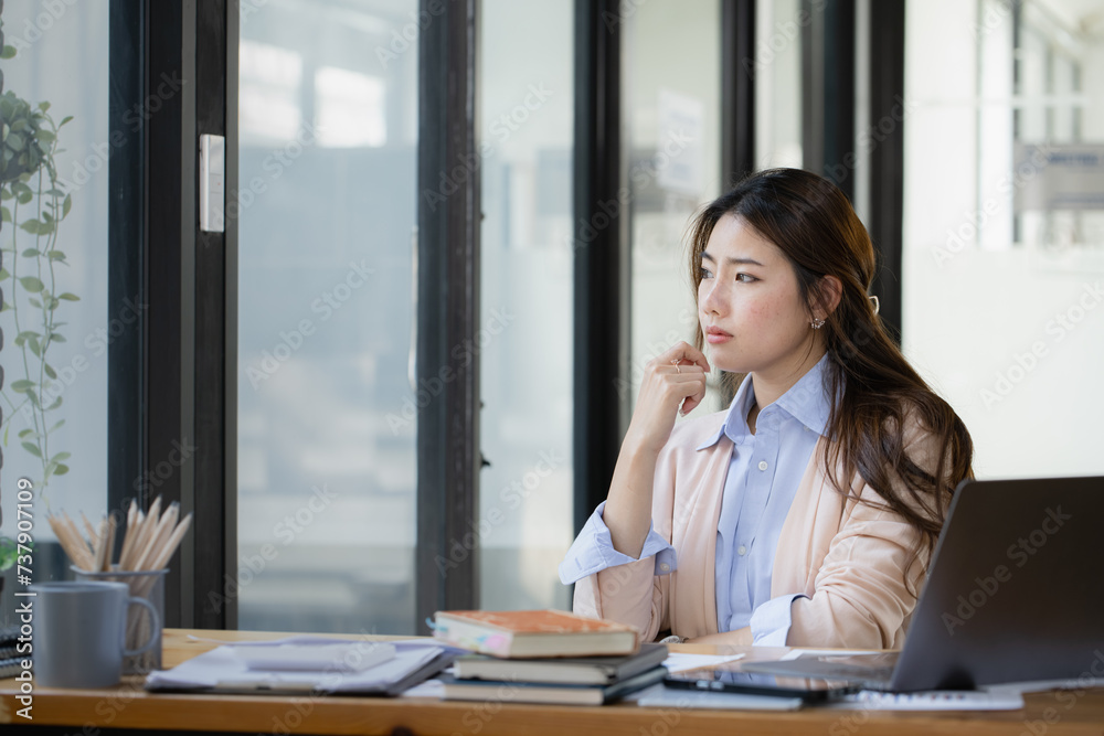 Happy asian young businesswoman using laptop with business finance chart sitting at office working space, Business finance and accounting woman concept. Happy asian young businesswoman using laptop with business finance chart sitting at office working space, Business finance and accounting woman concept.