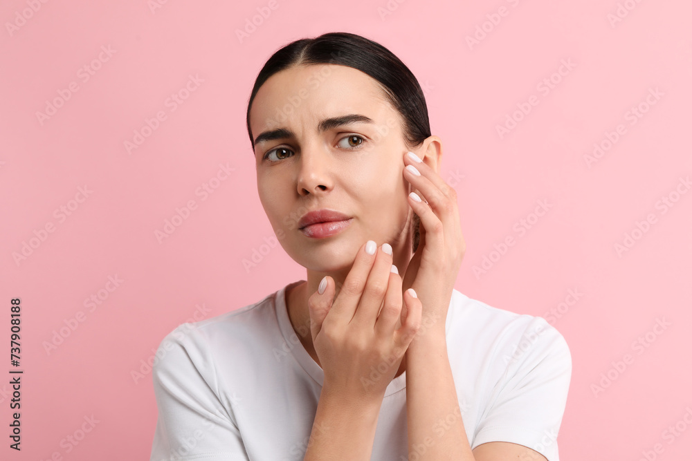 Woman with dry skin checking her face on pink background Woman with dry skin checking her face on pink background