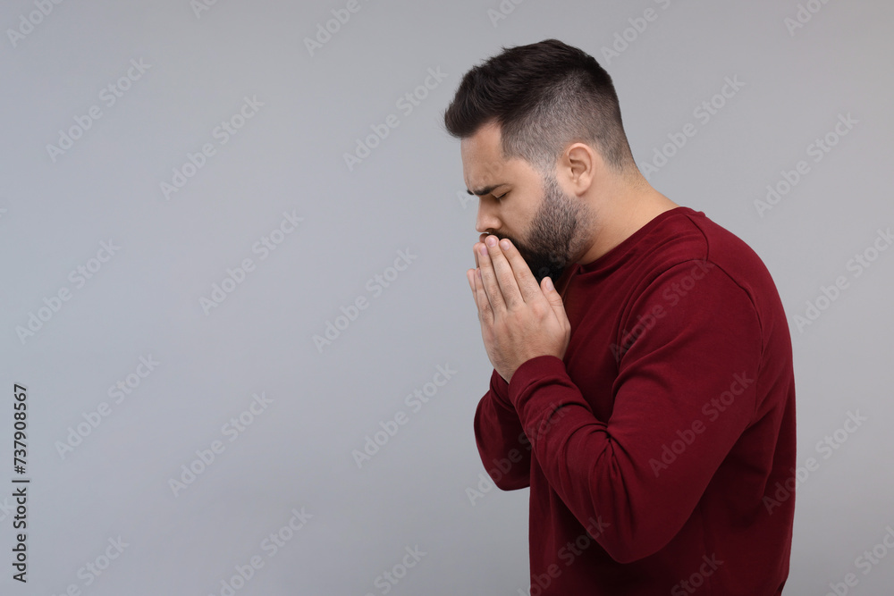 Sick man coughing on gray background, space for text Sick man coughing on gray background, space for text