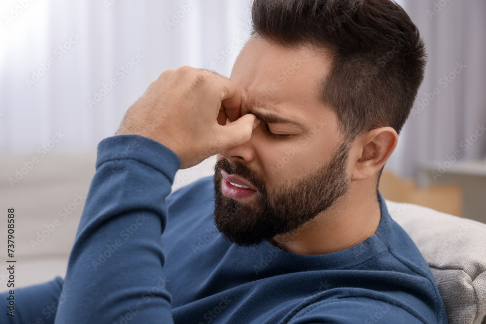 Unhappy man suffering from headache at home Unhappy man suffering from headache at home