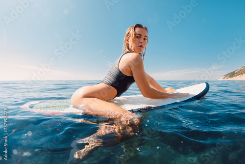 Photography Attractive sexy surf girl on surfboard in blue ocean and looking at camera