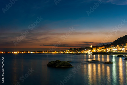 night town coast with flashlights from embarkment and reflection in sea gulf water with golden urbal lights and blue hour sky on background of landscape