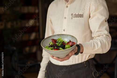 Close up of a man holding a bowl of salad in a restaurant .chicken liver salad