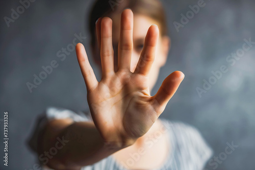 Woman raised her hand for dissuade, campaign stop violence against women. Grey background. photo