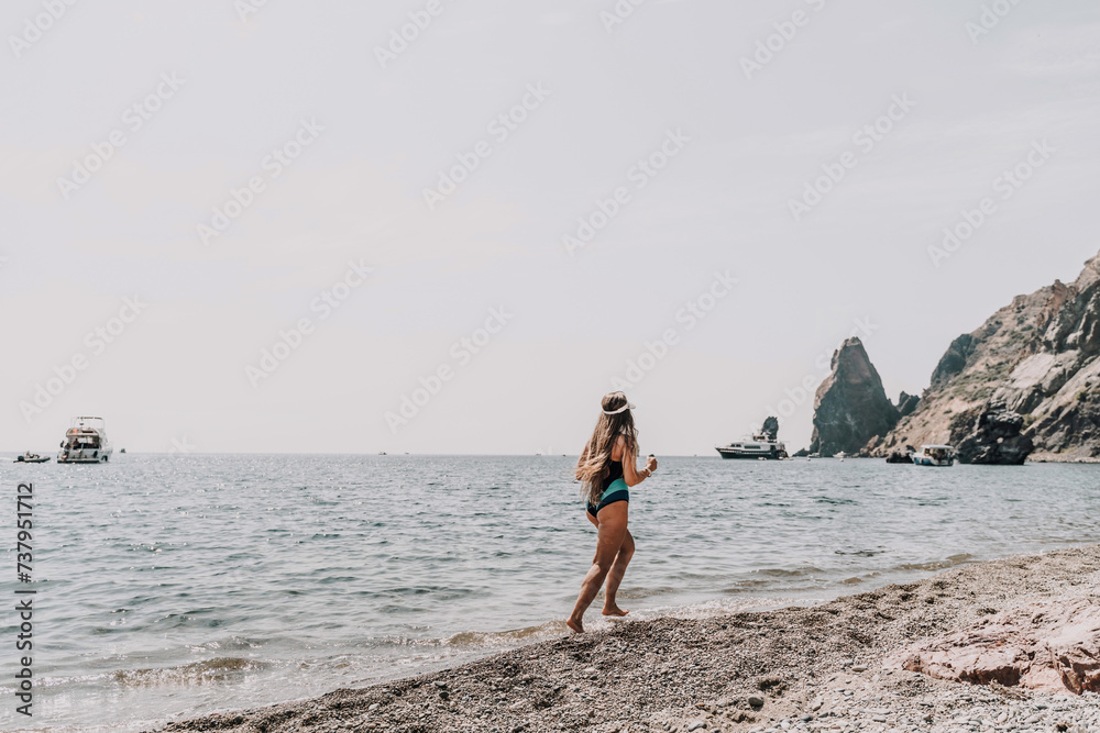 Woman beach vacation photo. A happy tourist in a blue bikini enjoying the scenic view of the sea and volcanic mountains while taking pictures to capture the memories of her travel adventure. Woman beach vacation photo. A happy tourist in a blue bikini enjoying the scenic view of the sea and volcanic mountains while taking pictures to capture the memories of her travel adventure.