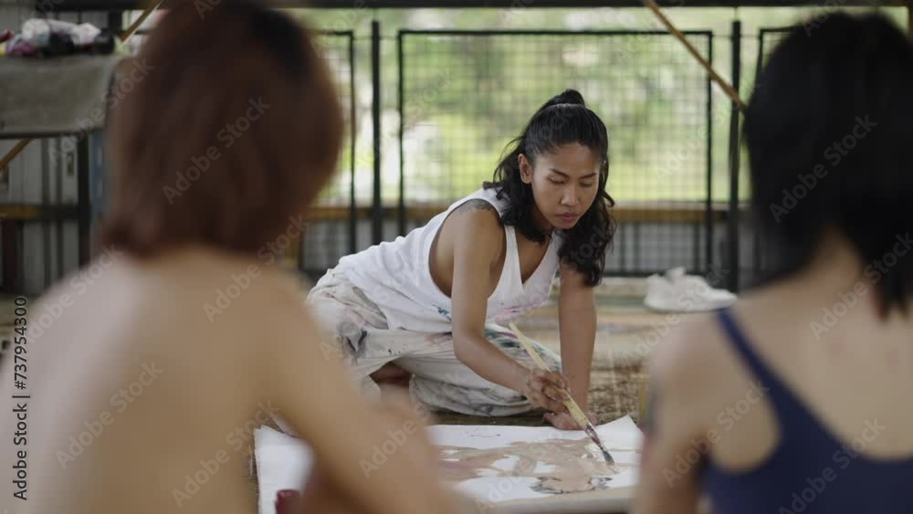 A woman on her knees captures two women on canvas A woman on her knees captures two women on canvas