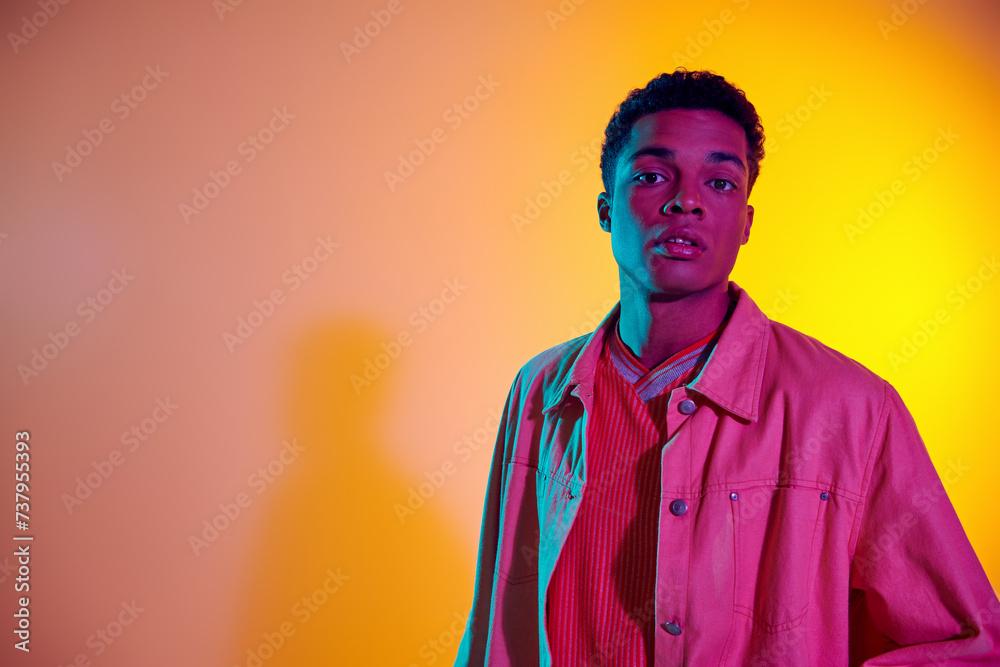 Obraz premium young african american man posing in trendy and casual clothing with vibrant gradient background