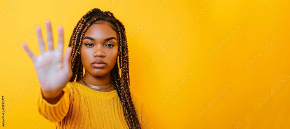 an African-American girl with pigtails on her head put her open palm forward. Stop sign. A girl on a yellow background with a call to stop. Place for text. Banner an African-American girl with pigtails on her head put her open palm forward. Stop sign. A girl on a yellow background with a call to stop. Place for text. Banner