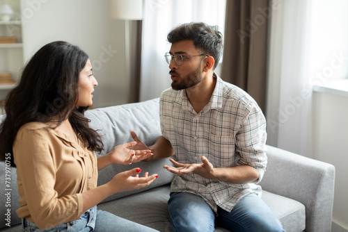 Married indian couple having quarrel, yelling at each other and gesturing, furious man shouting at his wife or breaking up ready for divorce photo