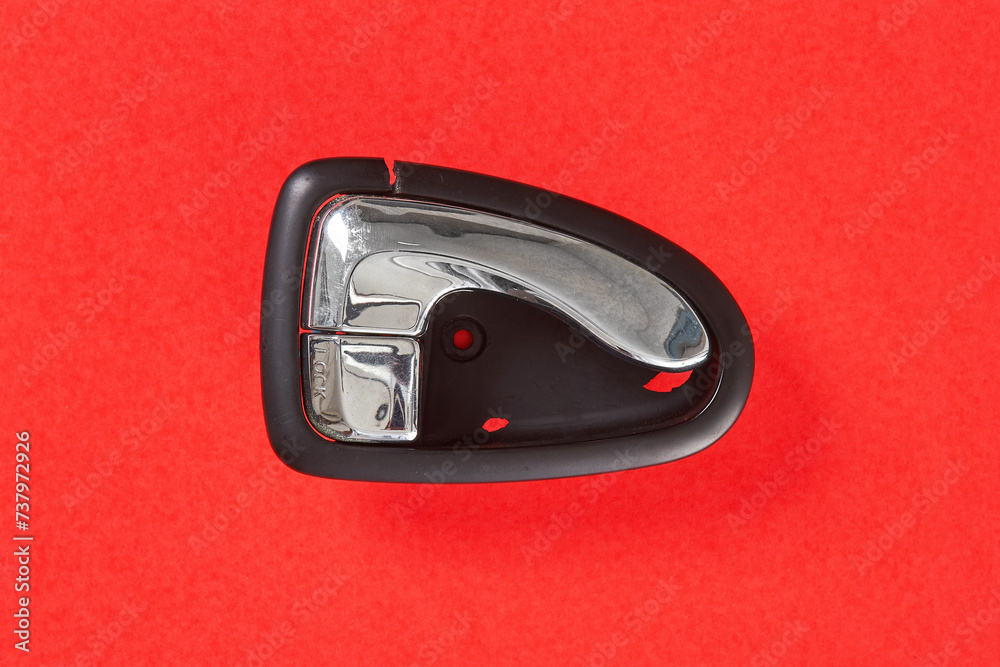 The right inner car door handle, which is damaged and needs to be replaced, is photographed with a red background The right inner car door handle, which is damaged and needs to be replaced, is photographed with a red background