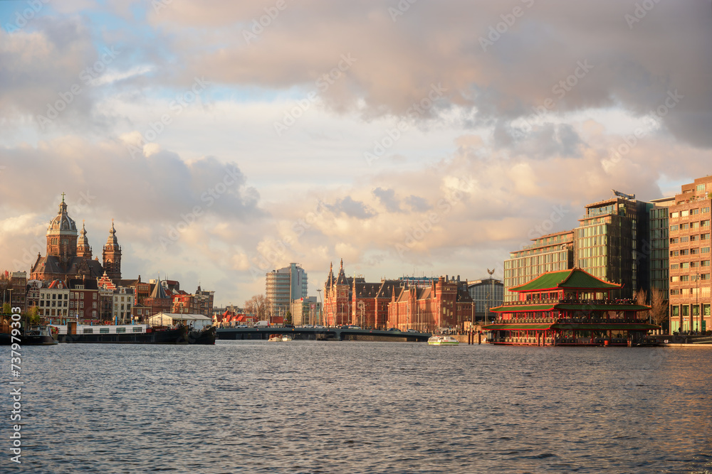 View from the water of Amsterdam, the capital of the Netherlands. Canals, the historic Church of St. Nicholas, the famous floating Chinese restaurant, Central Station.