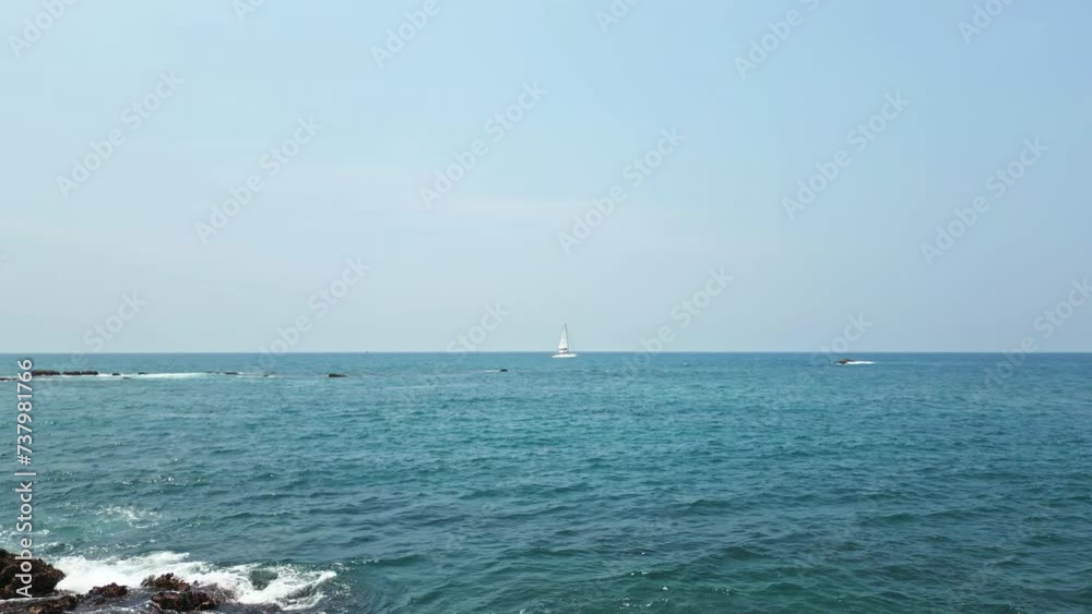 Sailing yacht cruises past rocky coastline on sunny day, clear blue sea surrounds vessel as navigates open waters, leisure marine travel scene, coastal adventure with ocean backdrop, nautical tourism. Sailing yacht cruises past rocky coastline on sunny day, clear blue sea surrounds vessel as navigates open waters, leisure marine travel scene, coastal adventure with ocean backdrop, nautical tourism.