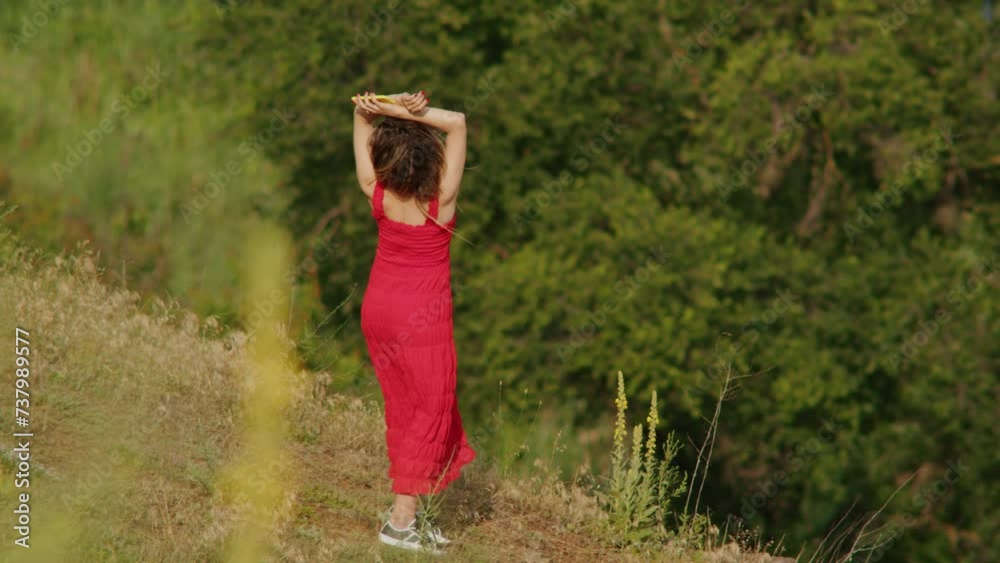 Woman in red dress standing on a hill in nature. Contemplation and freedom concept. Outdoor portrait with scenic background for design and print. Woman in red dress standing on a hill in nature. Contemplation and freedom concept. Outdoor portrait with scenic background for design and print.