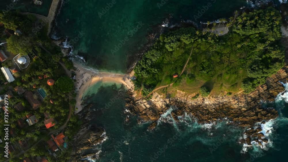 A little tropical island overgrown with jungle connected by thin sandy beach to the village A little tropical island overgrown with jungle connected by thin sandy beach to the village